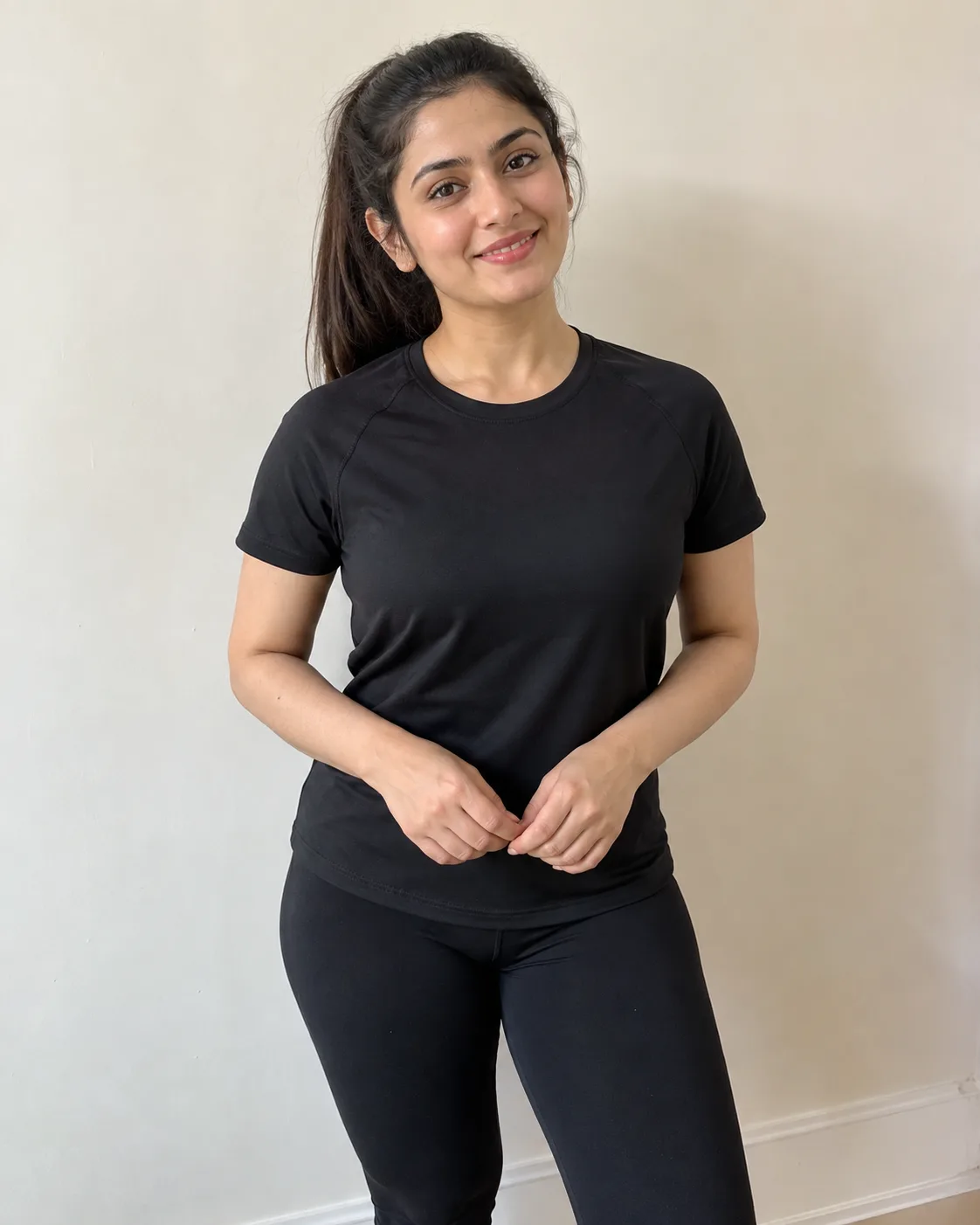 AI-generated photo of a smiling young woman with dark hair in a ponytail, in a black tee and leggings.